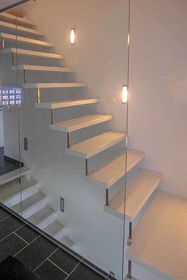 Treppe aus weiß lackierten Treppenstufen, wandseitig unsichtbar fixiert inkl. einem raumhohen Glaselement, Glaswand