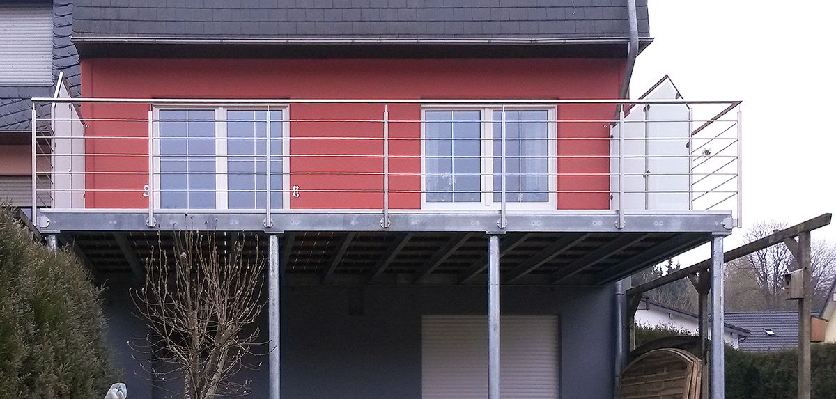 Anbaubalkon, Stahlbalkon verzinkt, an Fassade fixiert und freiseitigen Stützen, Bodenbelag aus Megawood und einem filigranen, modernen Geländer aus Edelstahhl