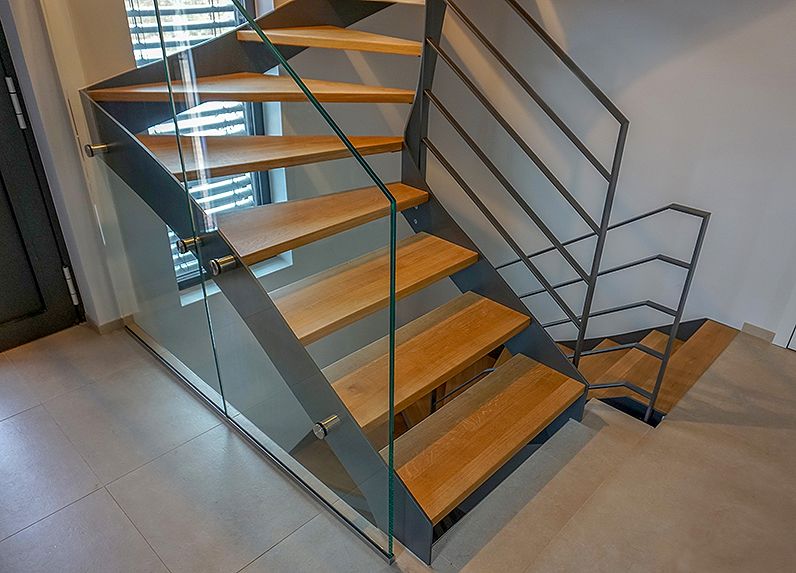 Wangentreppe mit Stufen in Eiche, filigranes und modernes Treppengeländer aus Flachstahl pulverbeschichtet und einem Glaselement.