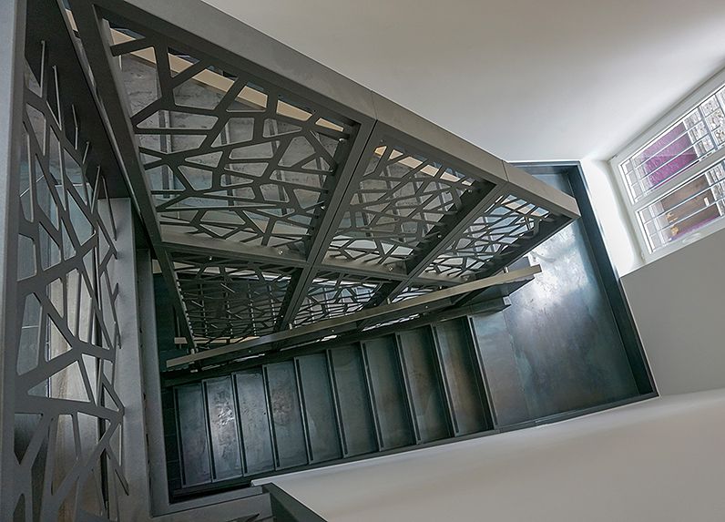 Treppe mit Schwarzstahl Stufen und Geländer mit Blechen in Design-Optik im Treppenauge.