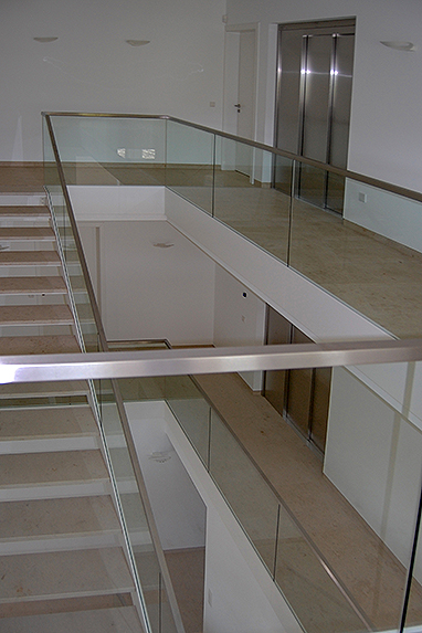 Galeriegeländer aus Glas mit einer weiß beschichteten Blende aus Aluminium, Treppenkonstruktion aus Stahl mit Granitstufen und Glasgeländer.