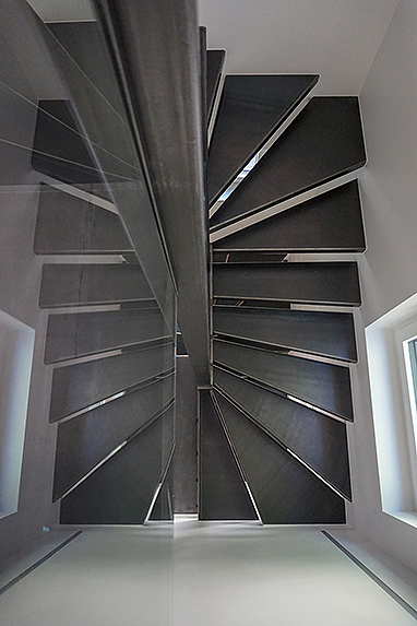Treppe im Innenbereich aus Stahl roh (Schwarzstahl) aus gekanteten Stufen und Geländer aus Glas, Ganzglasgeländer in U-Schienen